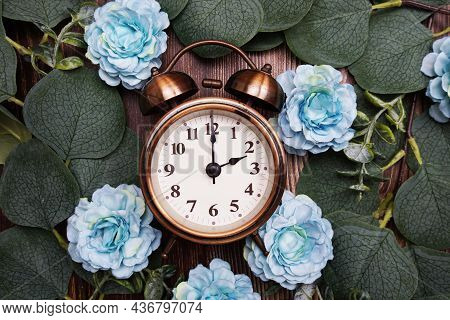 Alarm Clock With Eucalyptus Leaves And Flower Decorate On Wooden Background