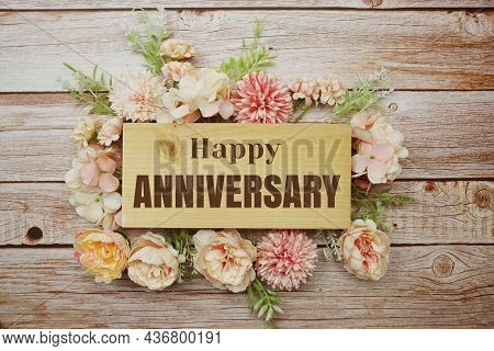 Happy Anniversary Text With Flowers Frame Decprate On Wooden Background