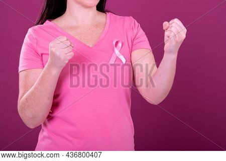 Midsection of caucasian woman in pink tshirt with ribbon and clenched fists. breast cancer positive awareness campaign concept digitally generated video.