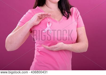 Midsection of caucasian woman in pink tshirt with ribbon gesturing. breast cancer positive awareness campaign concept digitally generated video.