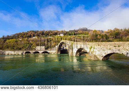 Italy, Lucca. The emerald cold water of the river reflects the ancient asymmetrical arches of the bridge. The bridge of Mary Magdalene crosses the Serchio River. 