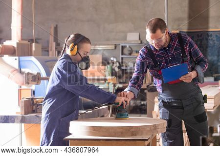 Experienced Carpenter Teaching Young Apprentice At Workshop