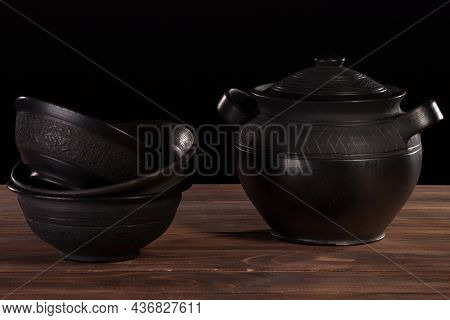 Black Pottery - Deep Bowls And Makitra On A Brown Wooden Table Against A Black Background. Studio Li