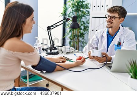 Man and woman wearing doctor uniform having medical consultation using tensiometer at clinic