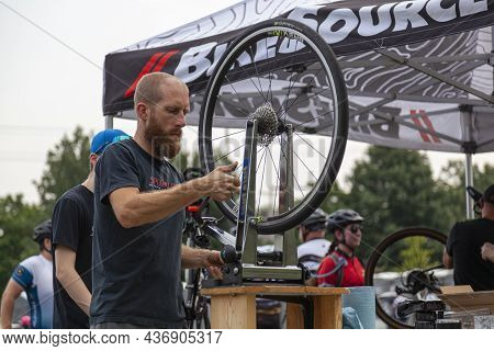 Columbus, Oh Usa 08-07-2021: A Young Caucasian Mechanic Is Using A Bike Wheel Truing Stand To Fix An