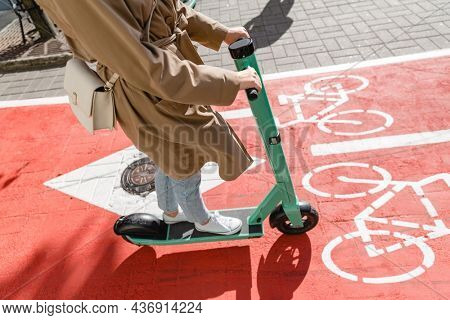 traffic, city transport and people concept - close up of woman riding electric scooter along red bike lane with signs of bicycles on street
