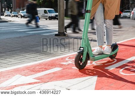 traffic, city transport and people concept - woman riding electric scooter along red bike lane with signs of bicycles and two way arrows on street