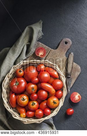 Fresh Red Tomatoes In Whicker Basket On Black Background. Flat Lay, Top View