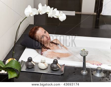 ผู้หญิงวางใน soapsuds ในการอาบน้ำที่เต็ม