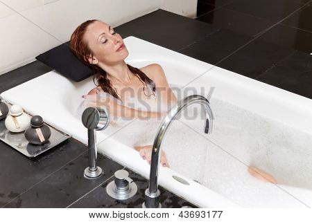 ผู้หญิงวางใน soapsuds ในการอาบน้ำที่เต็ม