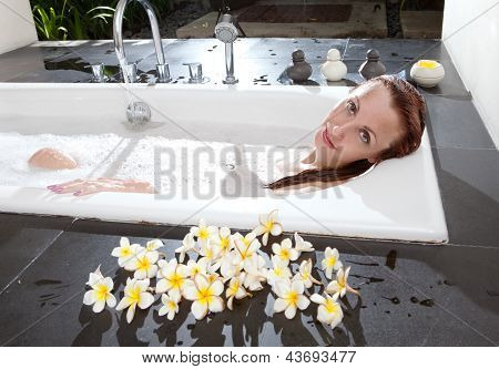 ผู้หญิงวางใน soapsuds ในการอาบน้ำที่เต็ม
