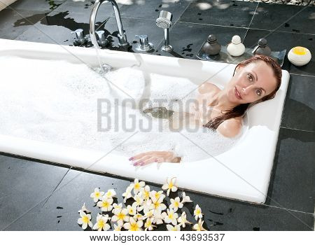 ผู้หญิงวางใน soapsuds ในการอาบน้ำที่เต็ม