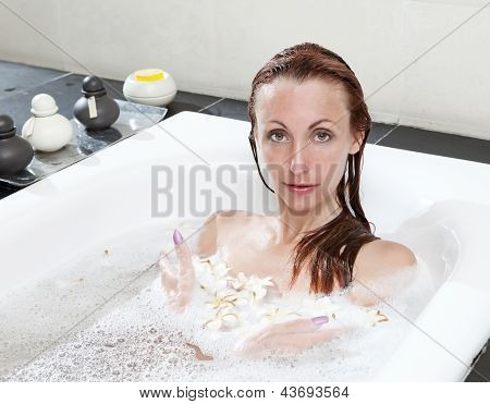 ผู้หญิงวางใน soapsuds ในการอาบน้ำที่เต็ม