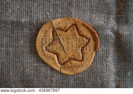 Brown sugar caramel candy cookies with a metal needle in the shape of a star. Concept of survival game