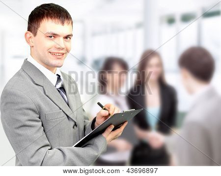 Retrato de homem de negócios confiante segurando o documento com a equipe no fundo do Blur