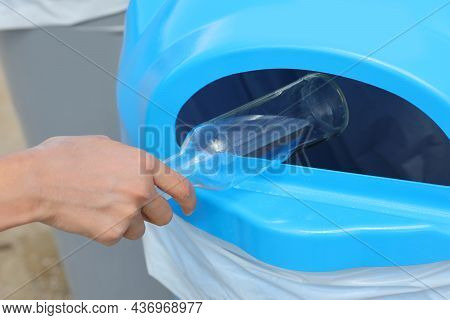Hand Of Young Boy Who Throws A Glass Bottle In The Recycling Bin