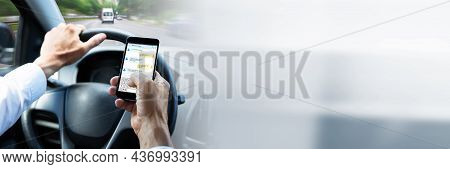 Man Typing Text Message On Mobile Phone While Driving Car
