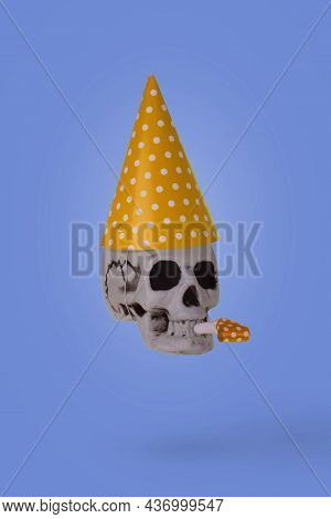Human Skull  With A Yellow Birthday Cap And Whistle  Isolated On A Purple Background. Minimal Holida