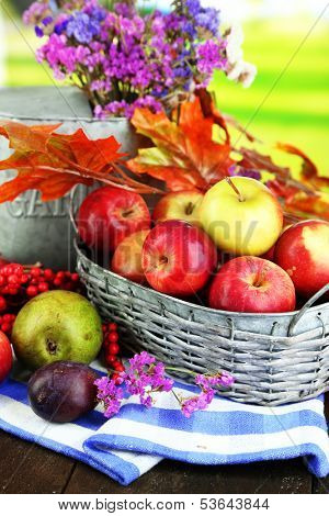 Juicy apples in basket on table on natural background