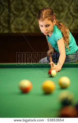 Teenage girl takes aim at a ball sitting on the pool table