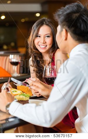 Asian Chinese couple - Man and woman - or lovers flirting and having a date or romantic dinner in a fancy restaurant 