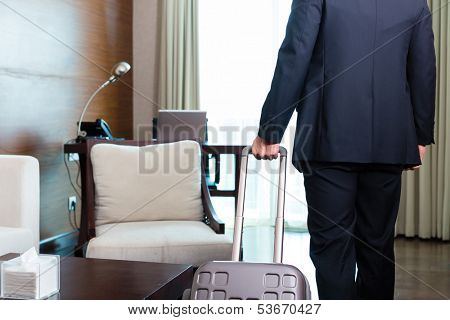 Manager or businessman on a business trip arriving to hotel room or suite after check-in with his trolley