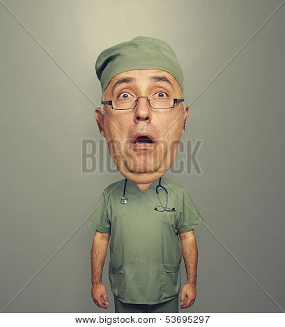 bighead amazed doctor in glasses and uniform over grey background