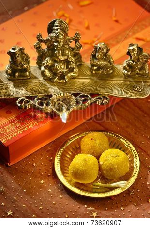 A metallic Ganesha statue lamp with Indian sweets.