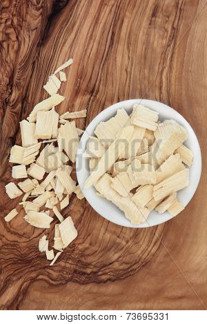 Quassia bark herb in a porcelain bowl and loose over olive wood background. Quassia amara.