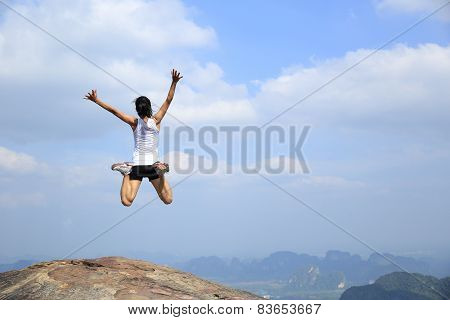Stock Photo: freedom young asian woman jumping on mountain peak rock