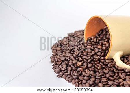 ceramic orange mug on a pile of roasted coffee beans