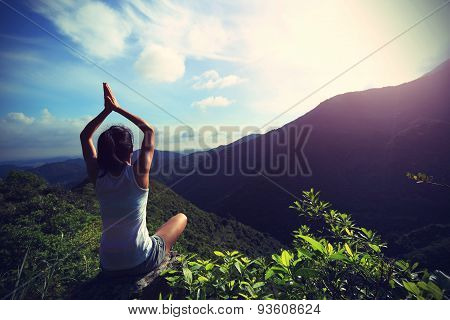 young fitness woman practice yoga at mountain peak rock
