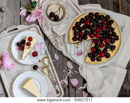 Cheesecake With Cherry, Two Slices On Saucers And Metal Tray  On A Wooden Table. .
