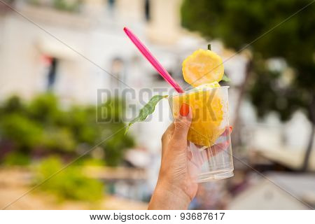 Girl's hand holding a glass with lemon ice cream.