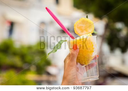 Girl's hand holding a glass with lemon ice cream.