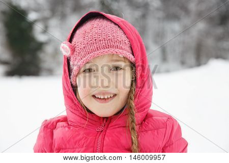 Beautiful girl with braids enjoying winter and snow dressed in warm clothes playing and catching some sun. Active family lifestyle outdoor and natural childhood carefree childhood concept.