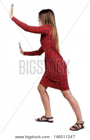 back view of woman pushes wall. backside view of person. The girl in red plaid dress that pushes it ahead.
