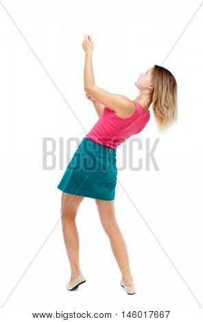 back view of standing girl pulling a rope from the top or cling to something. Isolated over white background. Blonde in a red sweater and green skirt sitting on a rope.