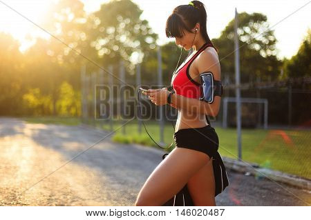 Young sport girl checking workout on smart watch in the street.Woman looking at the smart watch and smile