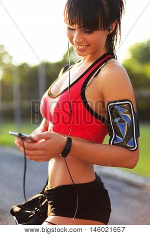 Young sport girl checking workout on smart watch in the street.Woman looking at the smart watch and smile