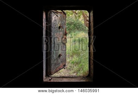 Open the door of the old bunker. The view from the dark nature behind a door.