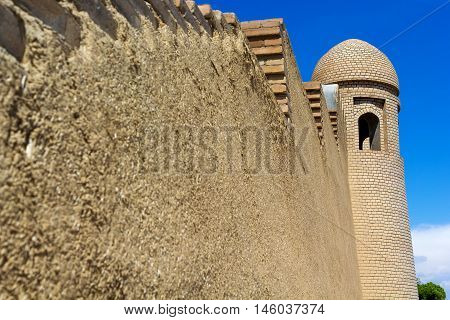 minaret of a mosque and a wall against the blue sky