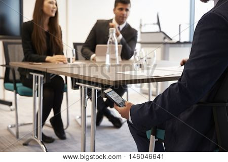 Businessman Discreetly Receiving Text Message During Meeting