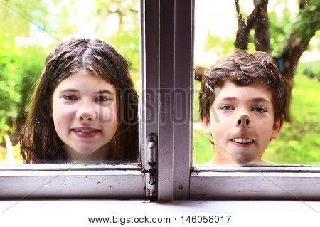 teen girl and boy siblings with nose pressed against the window close up portrait