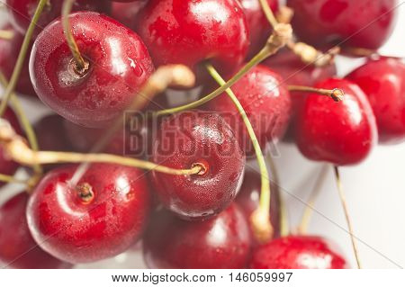 Macro shot of fresh red cherries with green stems, horizontal, sunlit