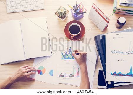 Top view of business man analyzing financial chart with laptop computer warm tone filter
