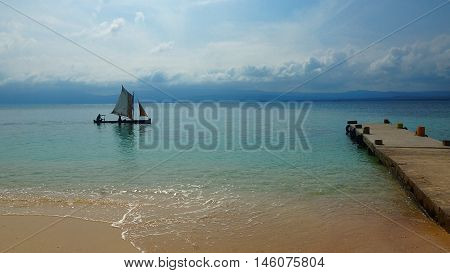 Small sailboat sailing close to the beach of Aguja Island, Las perlas / Panama
