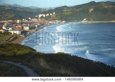 Waves coming on the beach of a quiet seaside town on a windy sunny summer morning shot from a hill