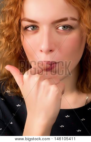 Close-up portrait of young beautiful girl with red hair licking her finger