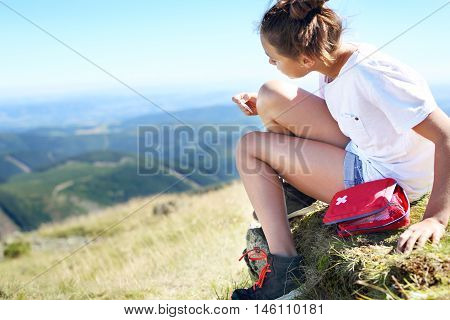 First aid kit in a backpack tourists. Child sticking plaster on knee.